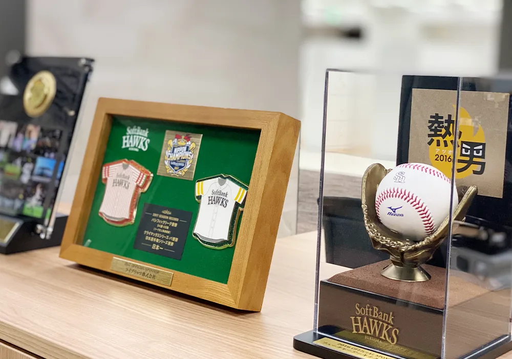 オフィスに飾られたプロ野球球団の記念パネルと、グローブに載った記念ボールの展示